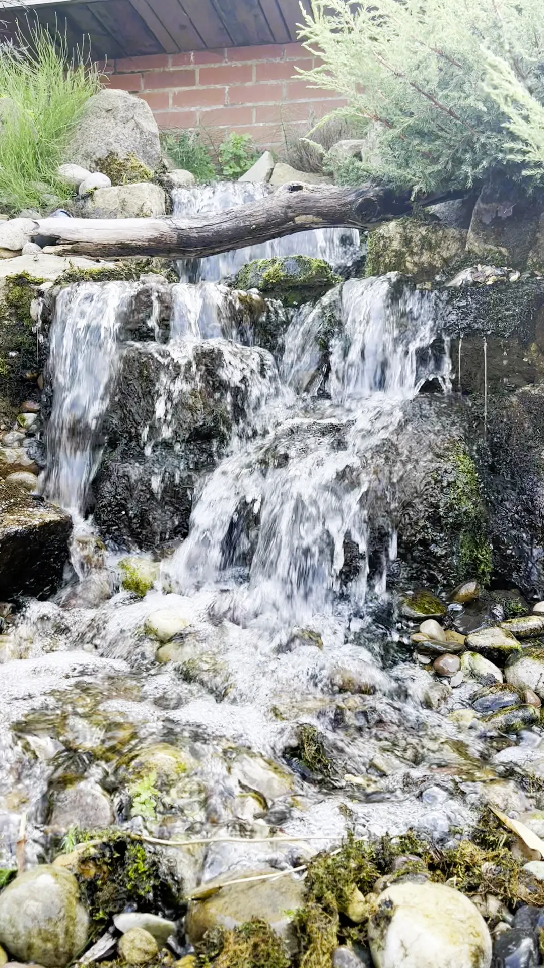 Natural stone waterfall flowing into a garden pond